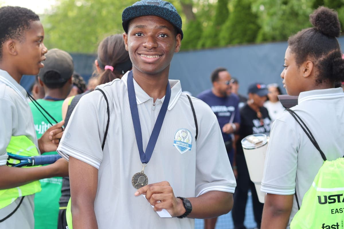 A teen smiling with his medal at a USTA youth event
