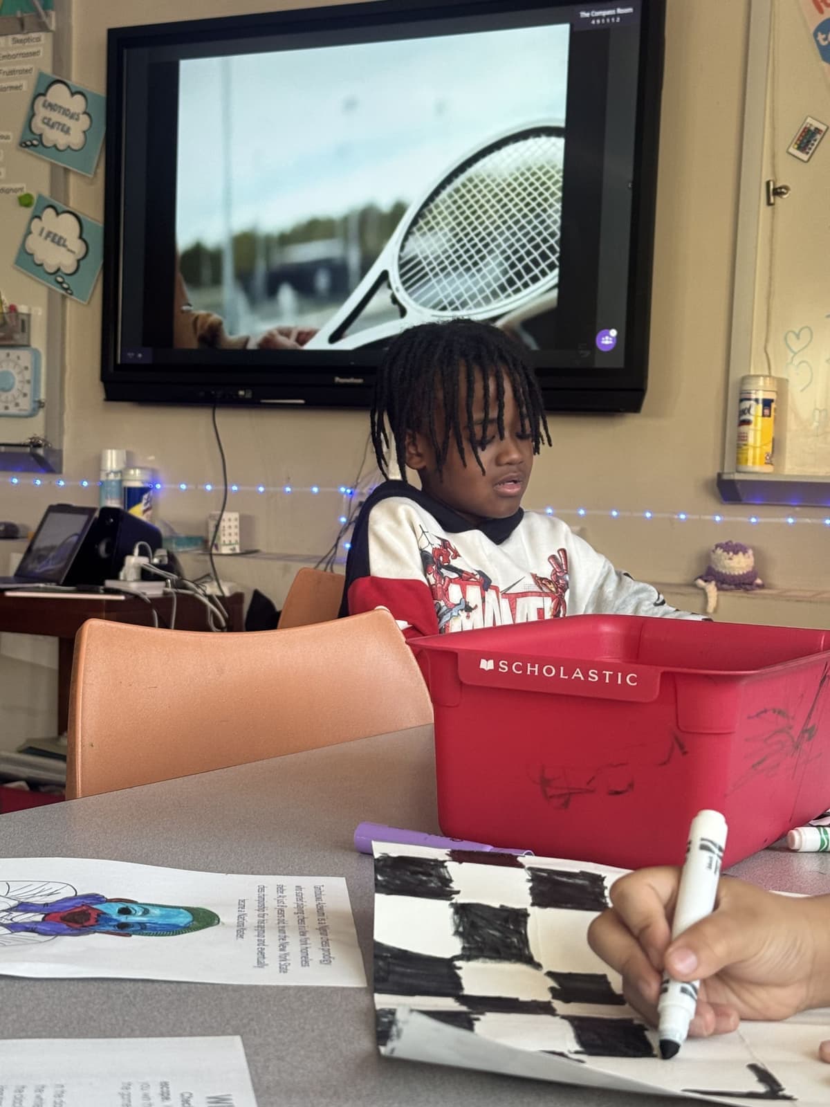 A student working at a classroom table beneath an emotions wall display