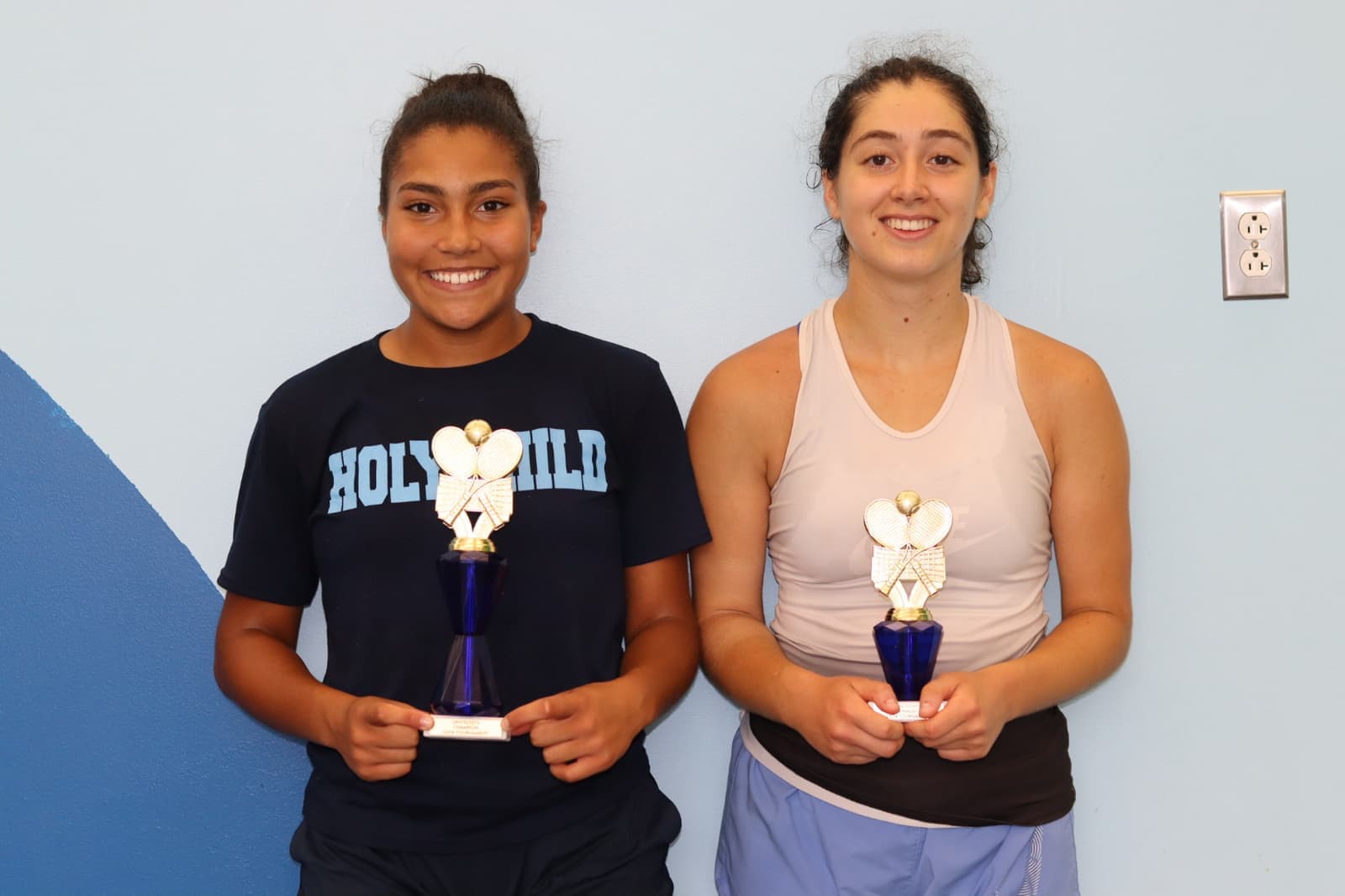 Two teen players smiling with their tournament trophies