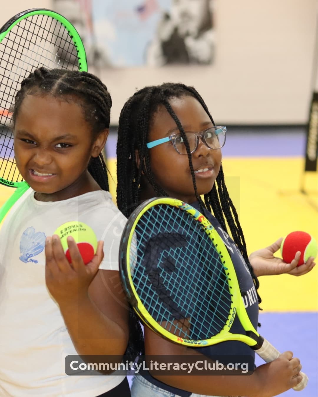 Two girls back to back holding rackets and foam balls