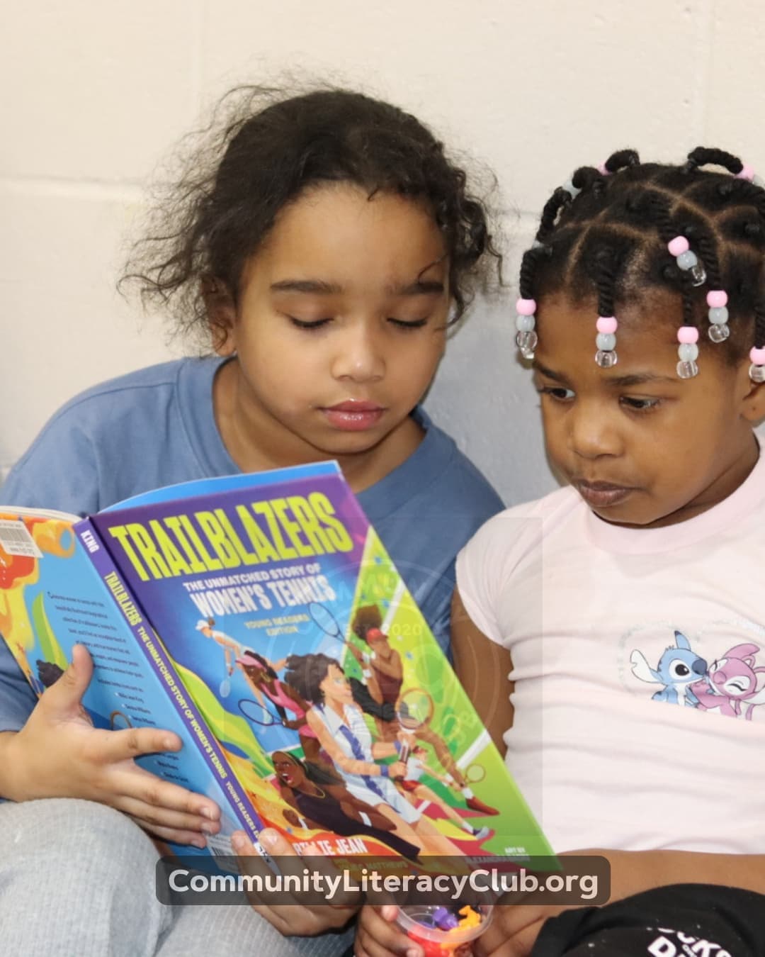 Two girls reading Trailblazers: The Unmatched Story of Women's Tennis together
