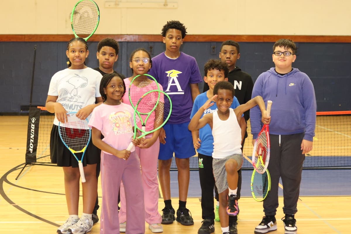 A group of young players holding rackets in the gym
