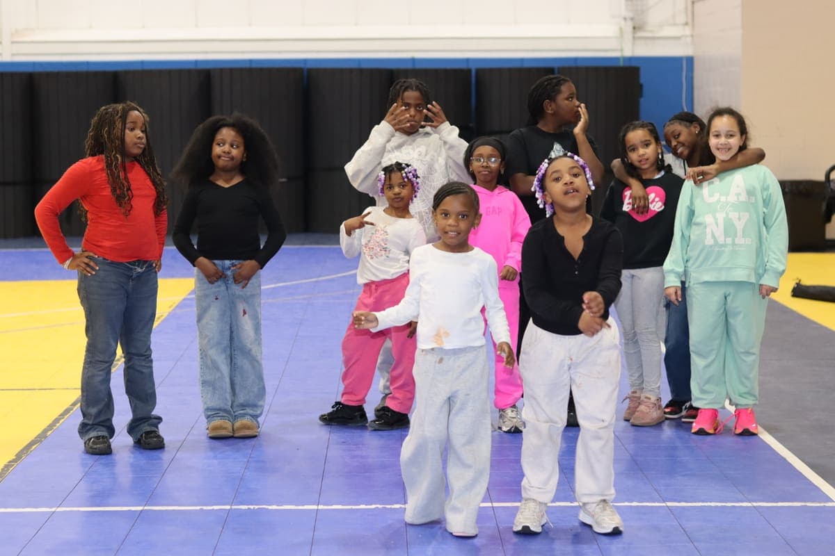 A group of kids lined up for a movement activity in the gym