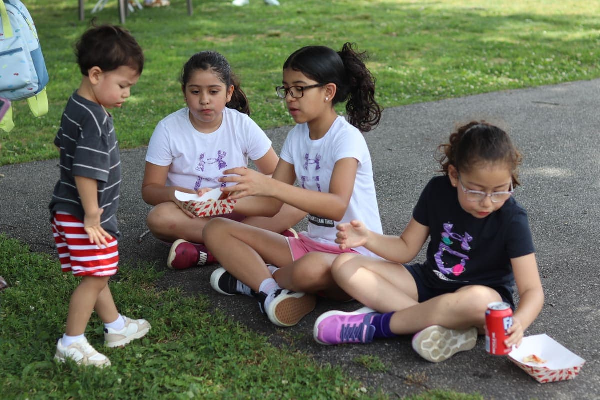 Kids sharing snacks on the grass at a CLC community day